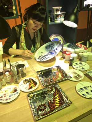 Artisan painting a porcelain plate