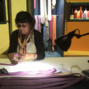 A lady hand stitching a silk tie