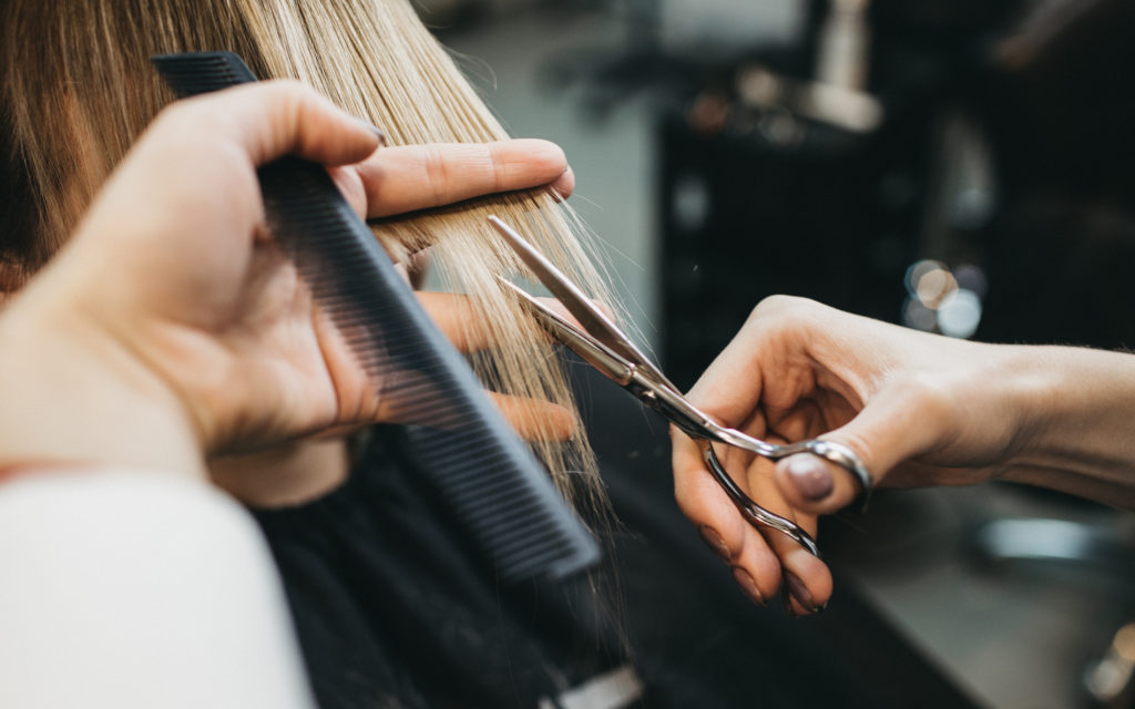 Applying makeup: This picture shows a woman having her hair cut. Hair colour is a topic discussed in a makeup lesson.