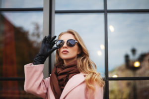 A woman displays her winter style by wearing an elegant coat, scarf and gloves.