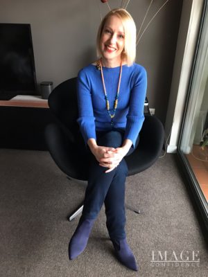 Woman sitting in a chair wears an outfit in various shades of blue