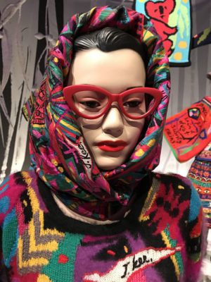 Jenny Kee mannequin wears her iconic red glasses and densely patterned scarf and jumper.