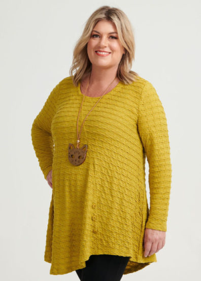 Woman wears long, golden yellow top with a necklace that sits below her bust and on her belly.