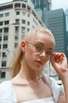 Woman with blond hair wears light coloured eyewear.