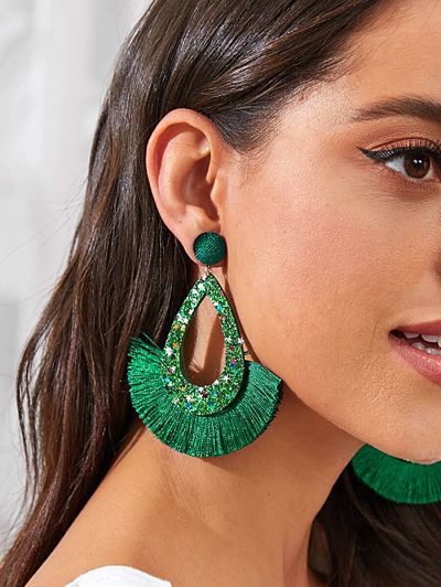 Woman wearing green sparkly earrings.