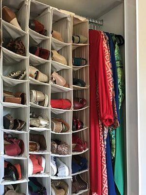 Closet organisation tip: Store shoes in hanging shoe pockets in your wardrobe. Image of many colourful pairs of shoes housed in shoe pockets.