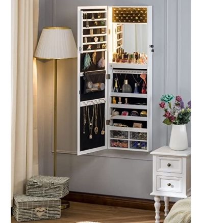 A large jewellery hangs on a wall. The door is open reeling jewellery, perfume bottles, and makeup.
