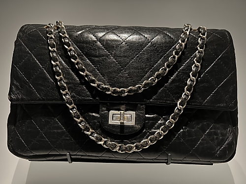 A classic, black Chanel 2.55 bag. It is quilted and features a metal chain strap that is threaded with a fine strip of leather to minimise noise. 