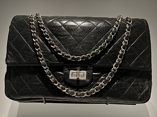 A classic, black Chanel 2.55 bag. It is quilted and features a metal chain strap that is threaded with a fine strip of leather to minimise noise.