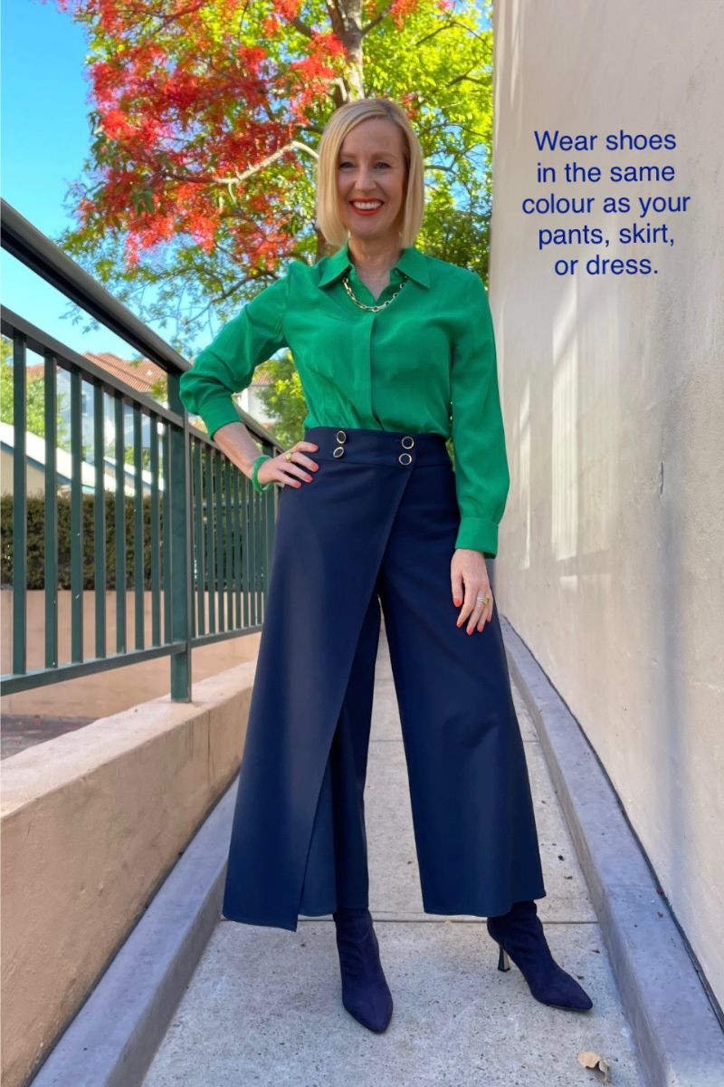 Woman wearing navy boots and navy pants to create the look of longer legs.
